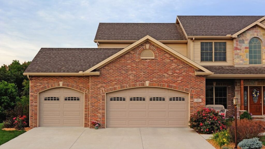 A Brick House With One Large and One Smaller Garage Door.