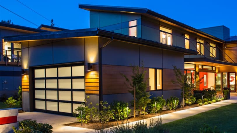 A building at dusk with a beautiful black and white garage door.