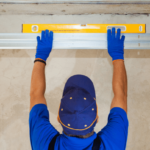 A garage door technician measures the level of a garage door track