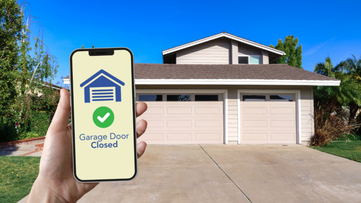 A phone reads “Garage Door Closed” on a smart technology app.