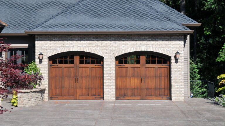 A large brick house with two beautiful wooden garage doors.