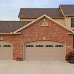 A brick house with two large garage doors that match the style.