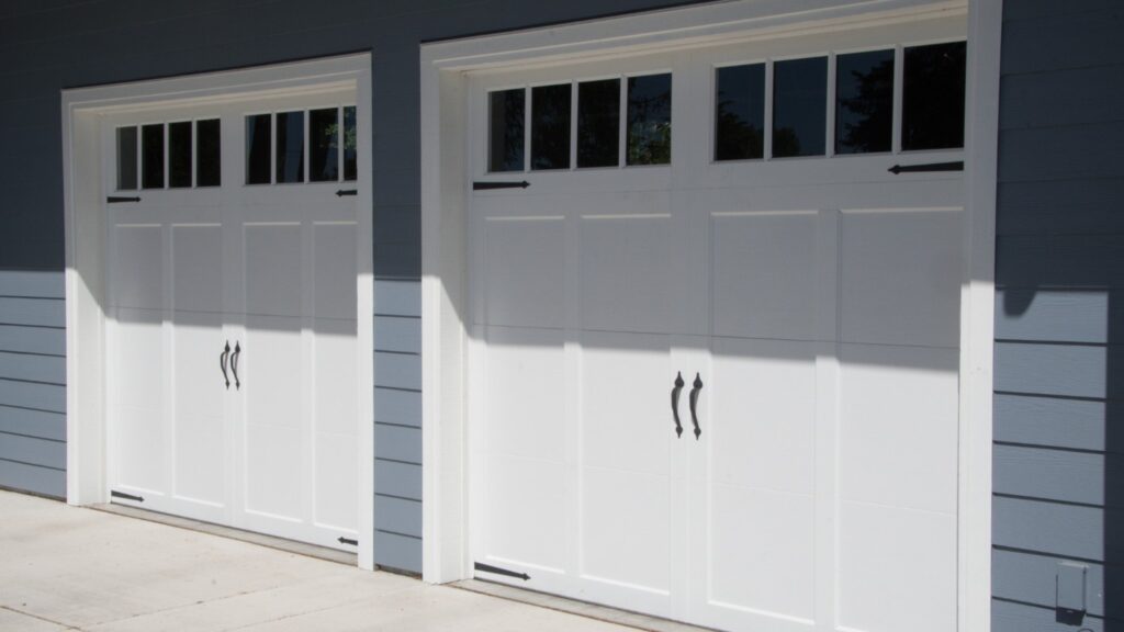 A bright white garage door against a slate grey colored house.