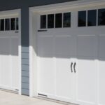 A bright white garage door against a slate grey colored house.