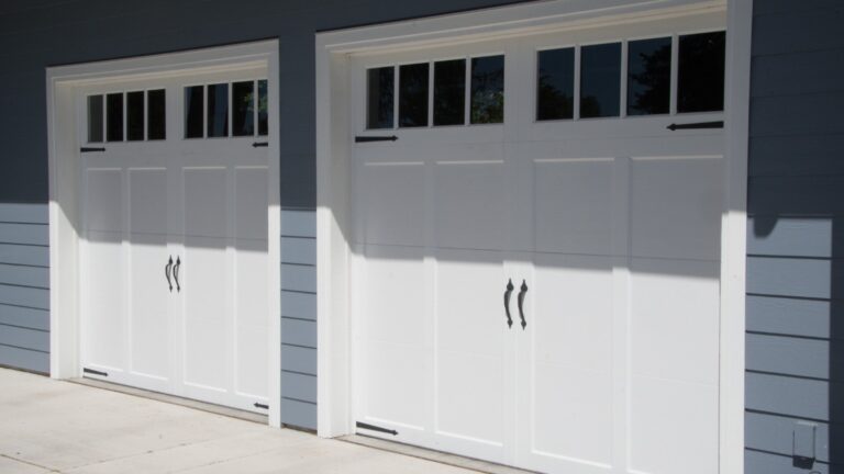 A bright white garage door against a slate grey colored house.