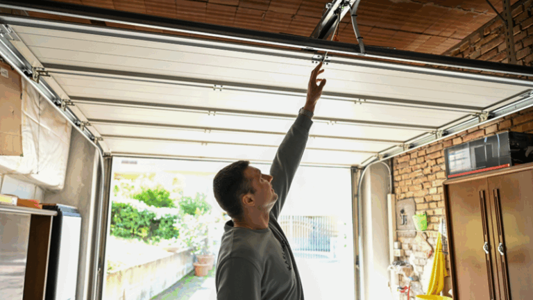A man reaches up to grab the safety rope on his garage door.