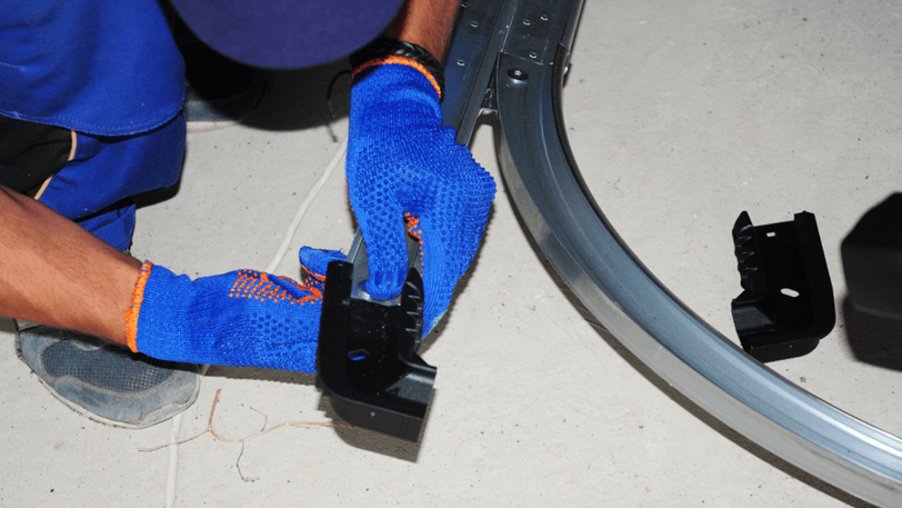 A garage door technician repairs the track on a new garage door.