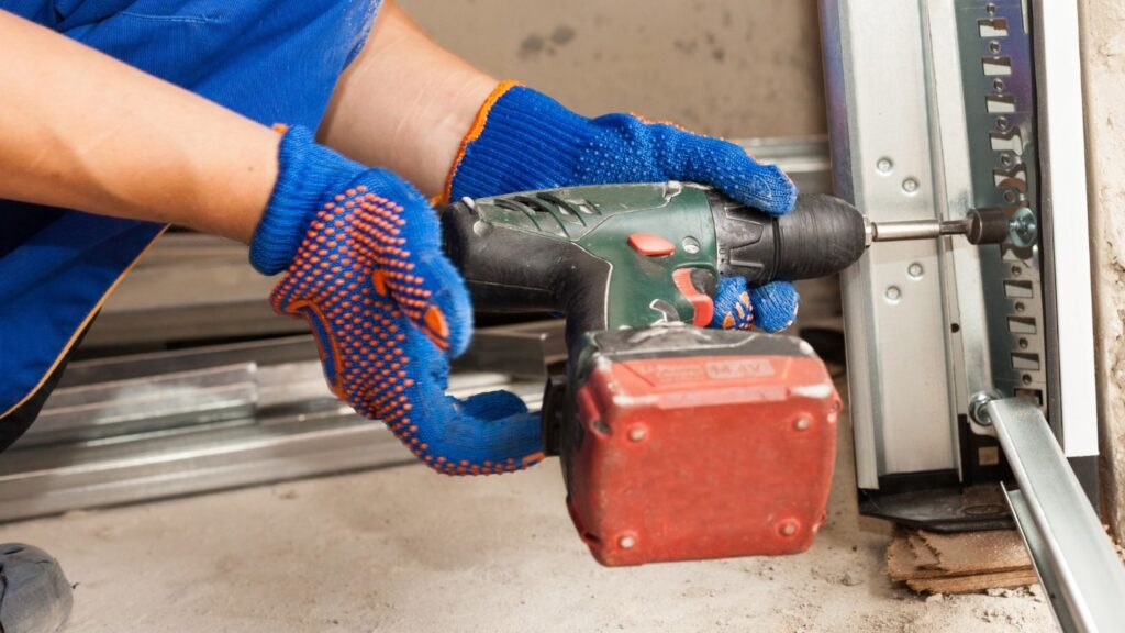 A garage technician tightens the bolts on a garage track.