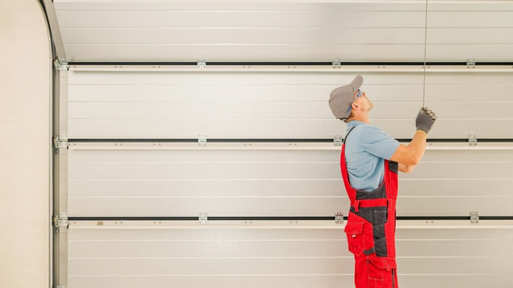 A garage technician uses a long tool to adjust the garage door.