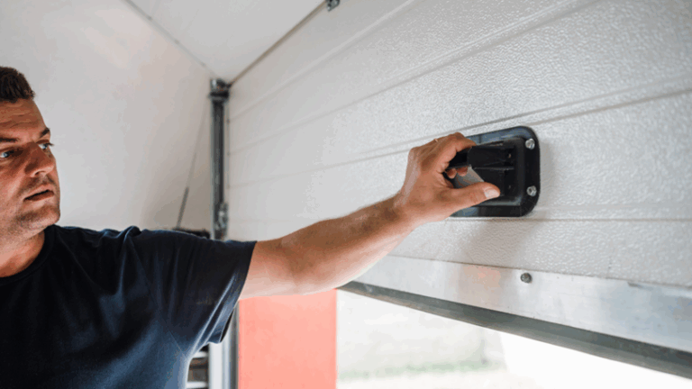 A man pulls up on the interior handle of a garage door.