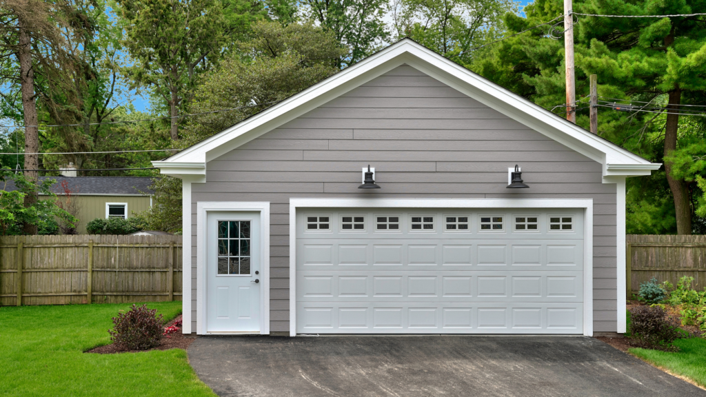 A detached two car garage with a driveway next to a lush green lawn.