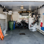 An open garage with tools, a refrigerator, bicycles, and other property inside it.