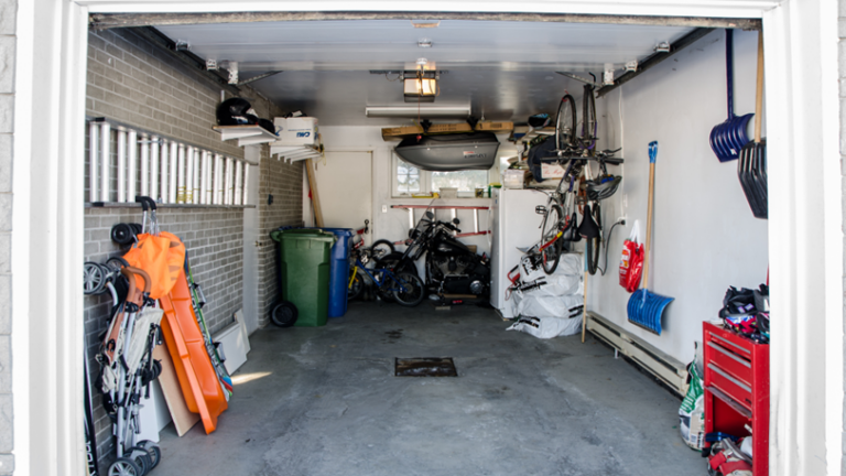 An open garage with tools, a refrigerator, bicycles, and other property inside it.